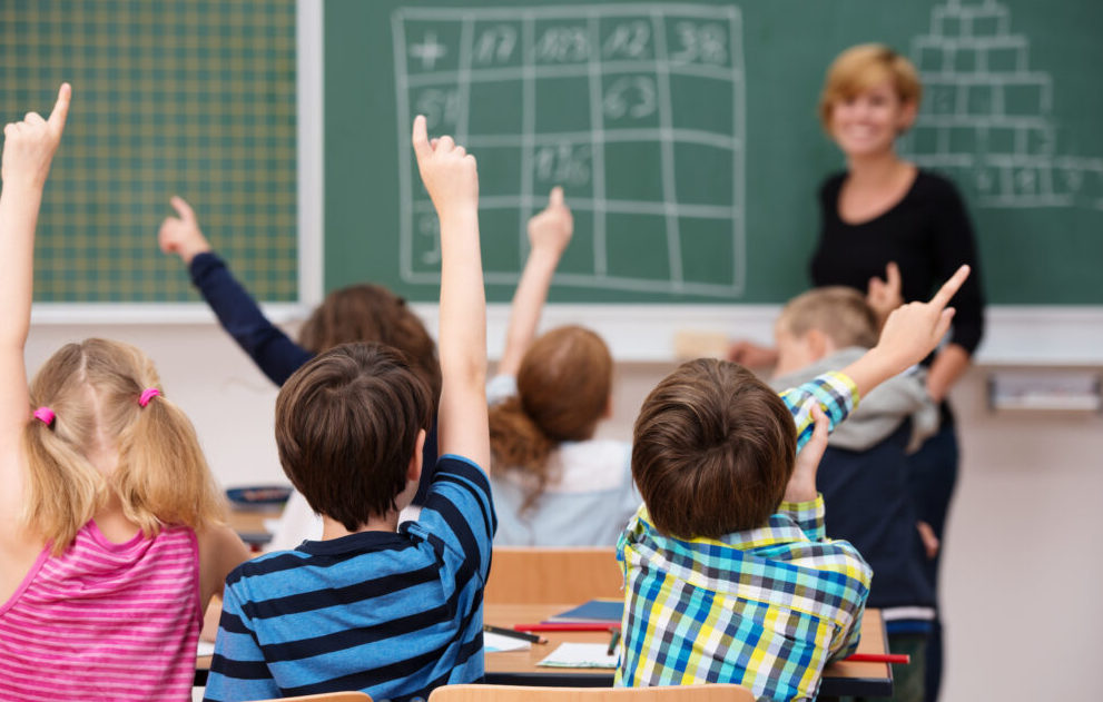 les élèves d'une classe lèvent tous la main pour participer